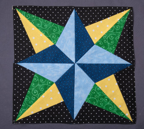 My favorite block from my first year of sewing is the 12" Blazing Star, designed by Eleanor Burns. It has a wonderful 3D effect caused by light and dark blues on the inner part of the star and yellow and green for the outer points. The background is black with white polka dots which really makes things pop!