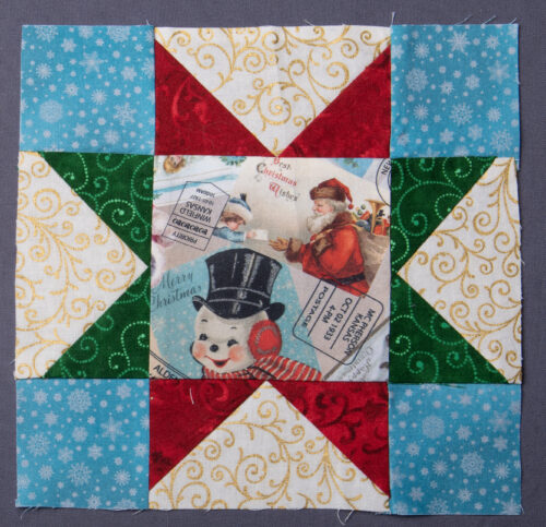 Variable star block, with a fussy cut Christmas image in the center, featuring a snowman and Santa Claus. The corners are blue with white snowflakes, and the stars are red and green with a white background.